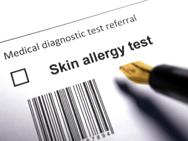 A close-up of a medical form titled "Medical diagnostic test referral" with a checkbox next to "Skin allergy test." A fountain pen tip is visible in the lower right, and there is a barcode under the test description.